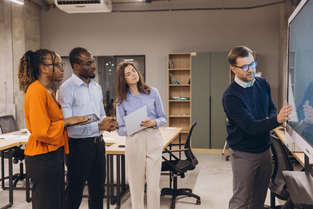 Procurement team collaborating around a digital whiteboard in a modern office
